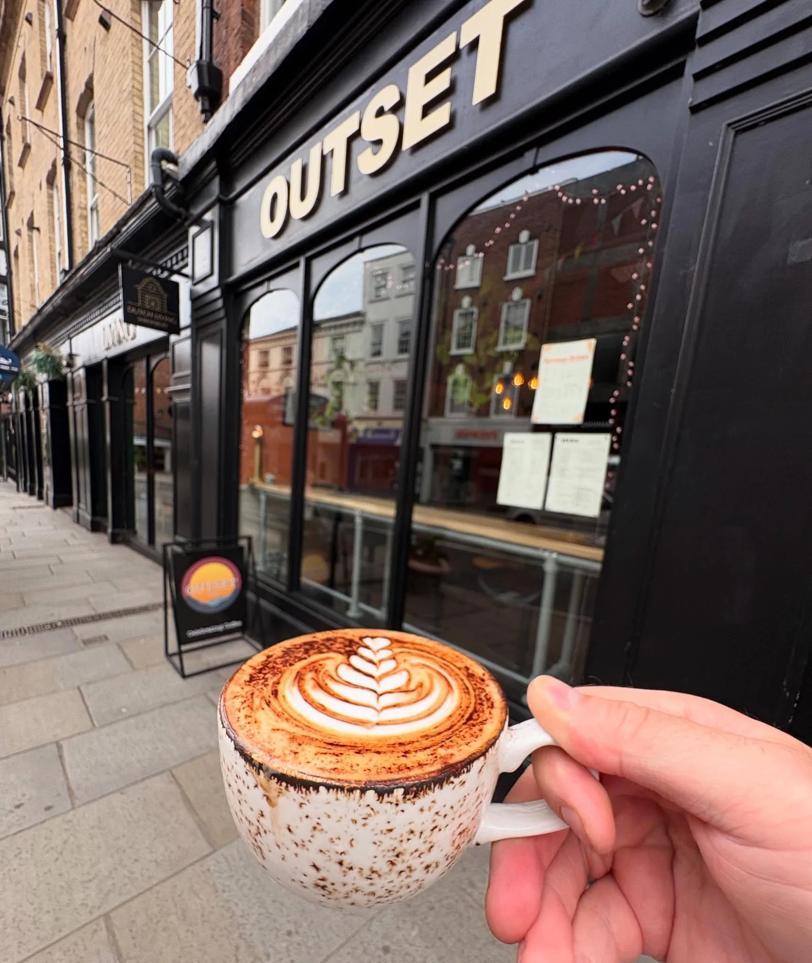 Latte held outside Outset Coffee